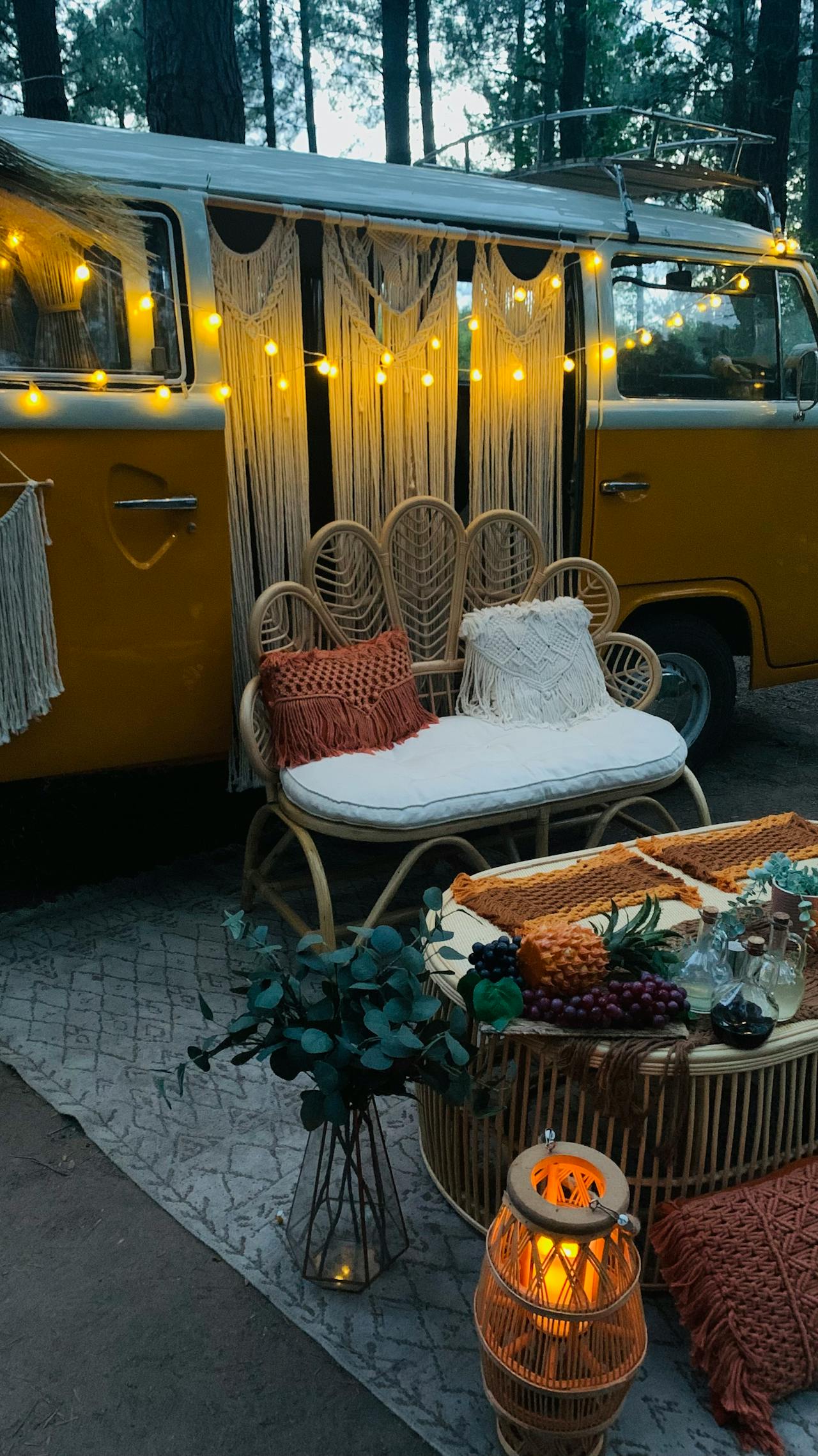 Battery-powered string lights illuminating a boho-style outdoor setup with vintage van, macrame wall hanging, rattan peacock chair, and woven lantern"